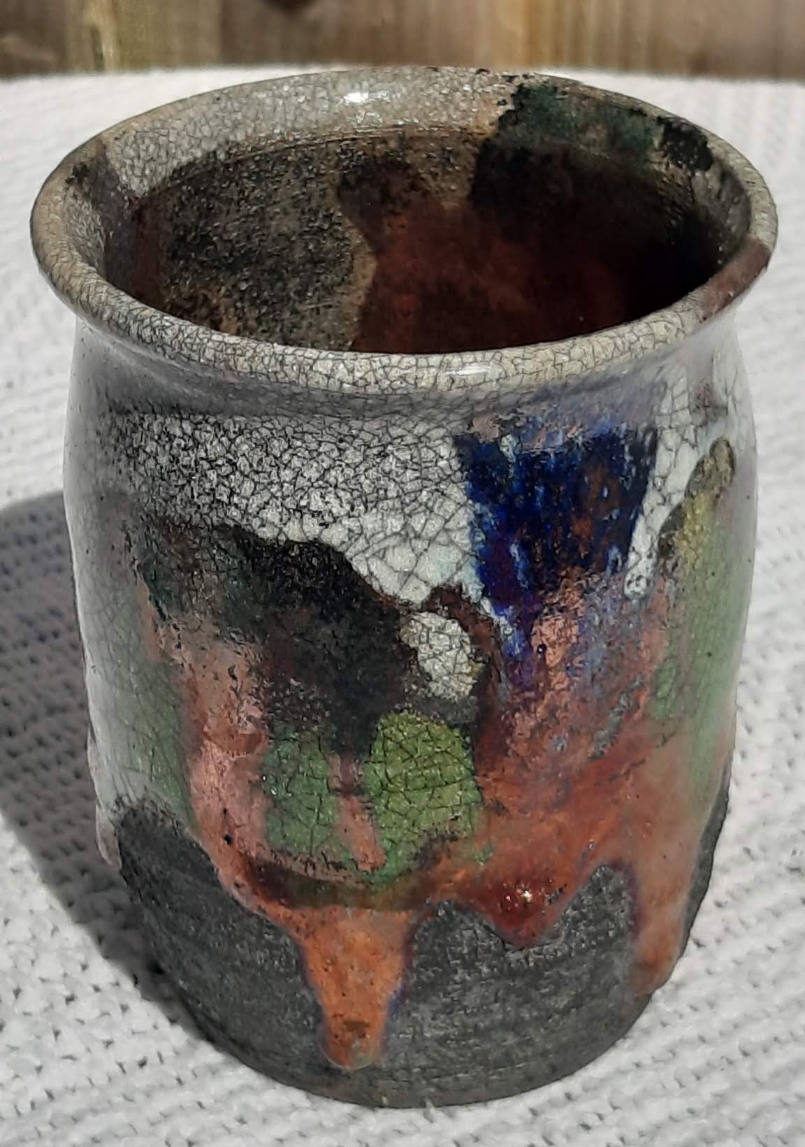 A Raku vase with patterns of blue, charcoal, bronze, green and grey.